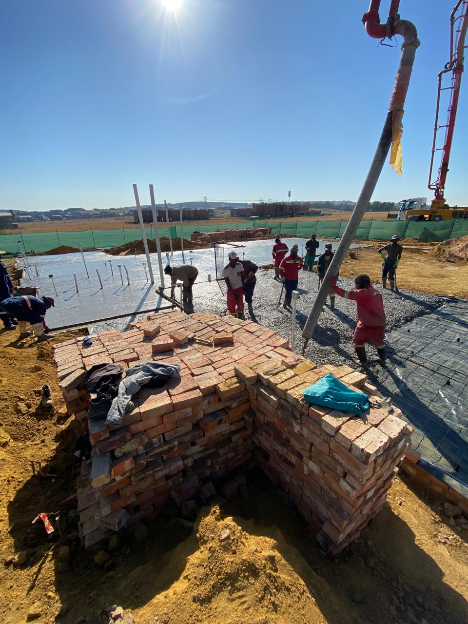 Pump-truck concrete pour with brick column in foreground